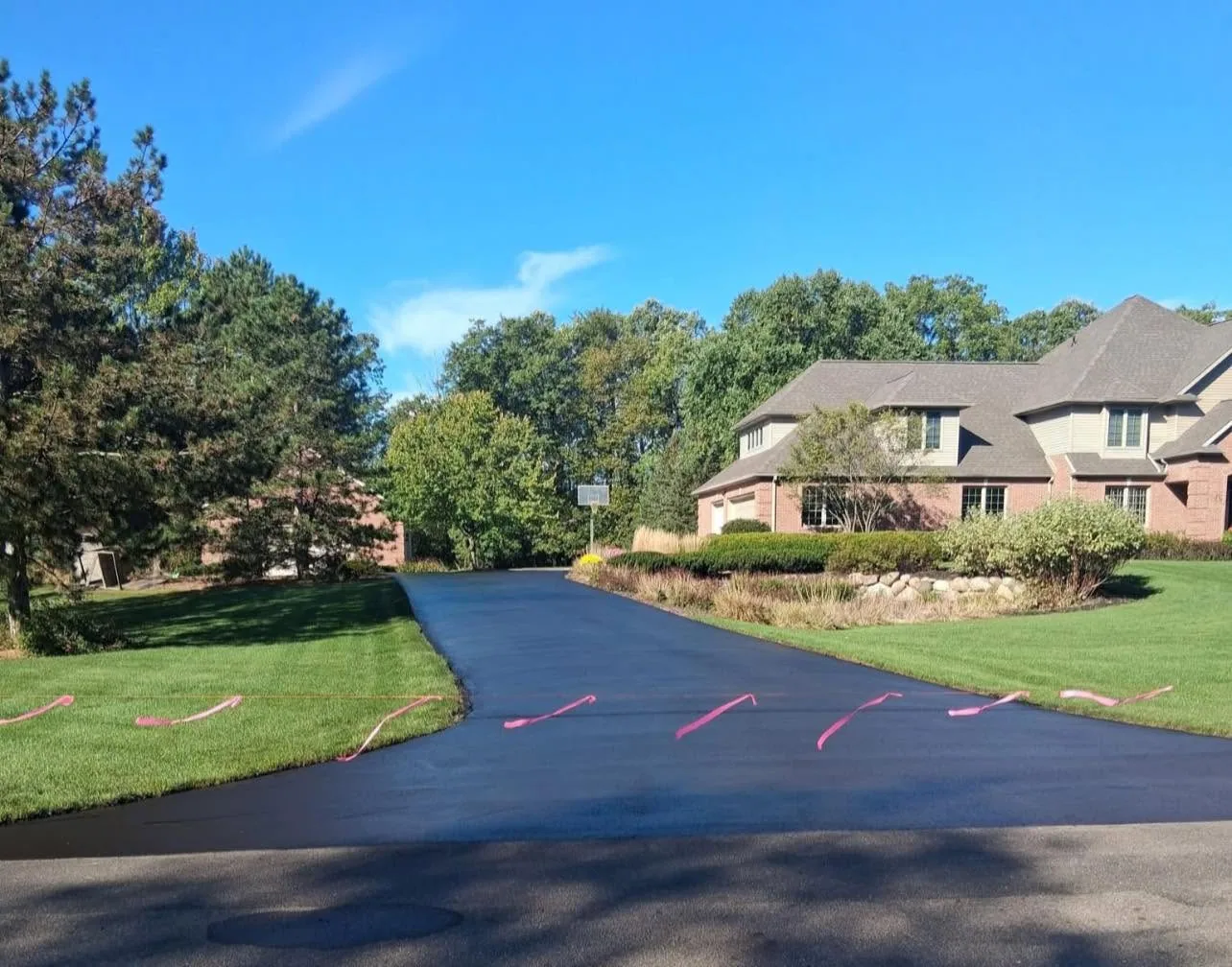 Freshly sealcoated residential driveway with pink flagging